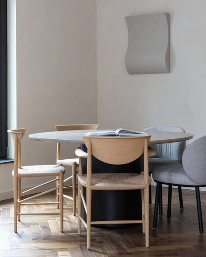 Contemporary dining room setup with wooden chairs and a modern wall art piece.
