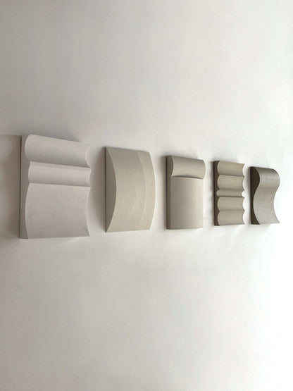 Contemporary wall art pieces in various colors including white, shadow white, dark lime, brown wood, and mud grey, made from biodegradable PLA with a sand texture finish.