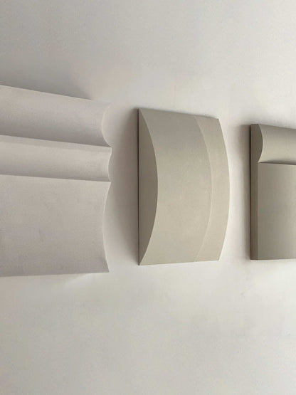 Contemporary wall art in white, shadow white, dark lime, brown wood, and mud grey tones displayed on a wall.