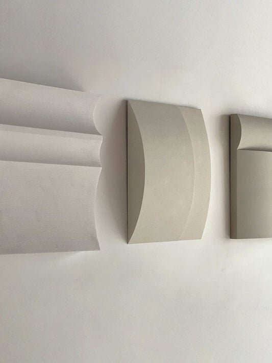 Contemporary wall art in white, shadow white, dark lime, brown wood, and mud grey tones displayed on a wall.